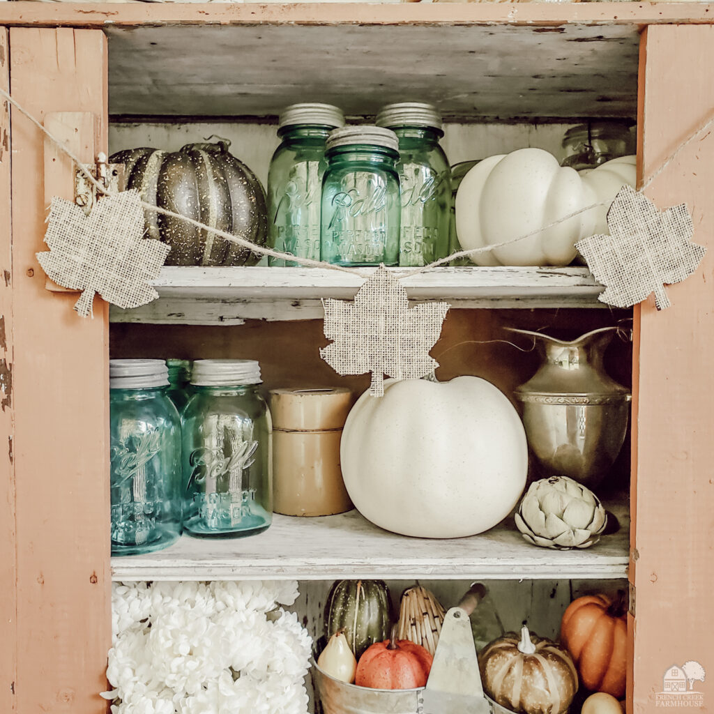 Burlap leaves garland hanging on chippy vintage jelly cupboard