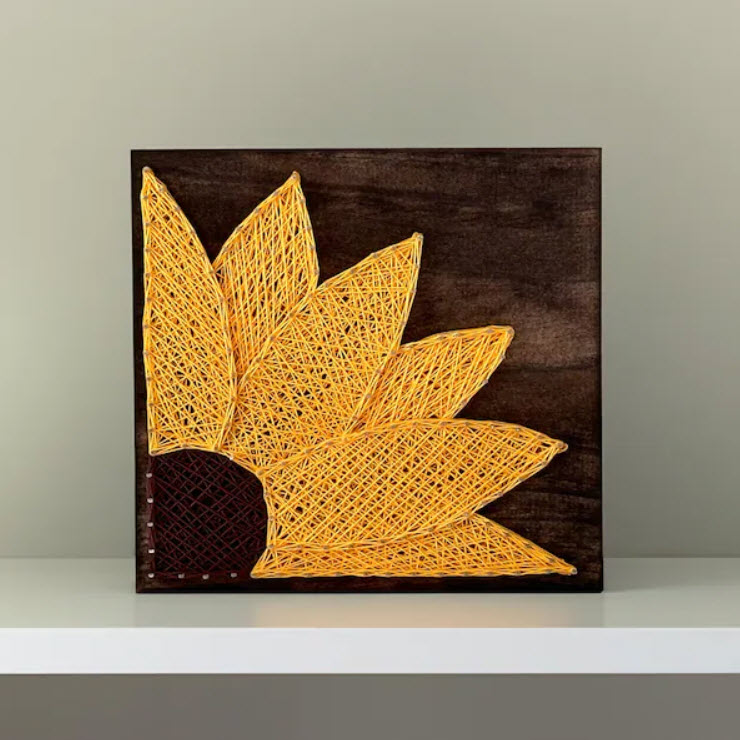 Sunflower string art on a dark stained wooden board